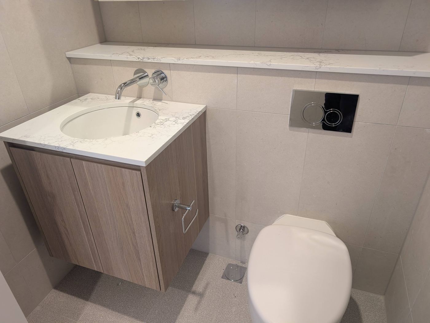 Completed apartment bathroom with wall-hung vanity and in-wall cistern at Infinity Park